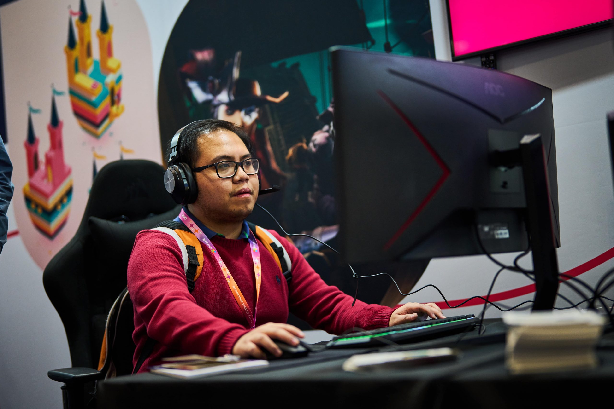 Man wearing headphones and a backpack playing a computer game at a gaming event