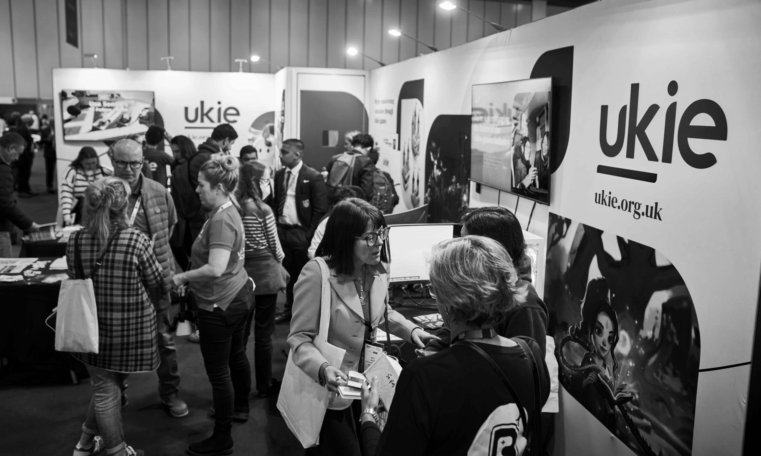 Black and white image of professionals at the Ukie stand when attending the BETT event