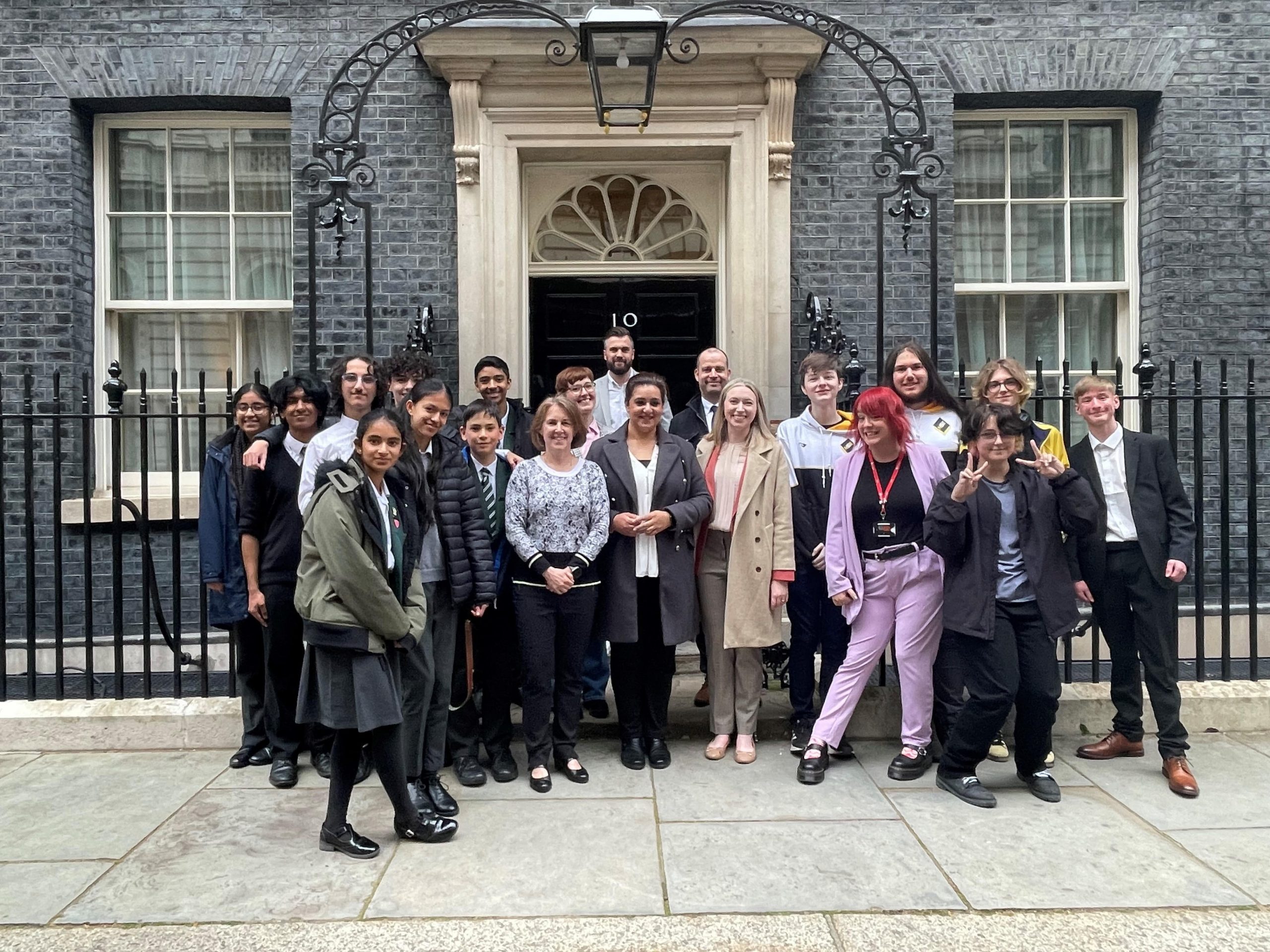 A group of professionals from Ukie standing outside the door of number 10 Downing Street with school children