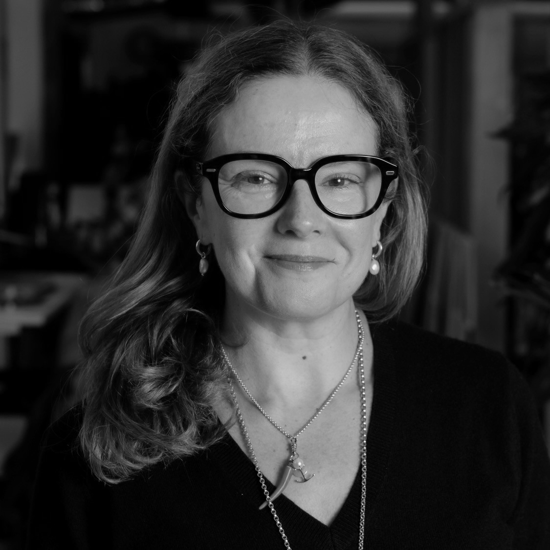 Headshot of a long haired women wearing glasses called Maria Sayans