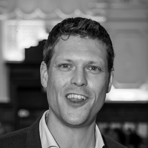 black and white headshot of a professional man at an event wearing a white shirt and black blazer