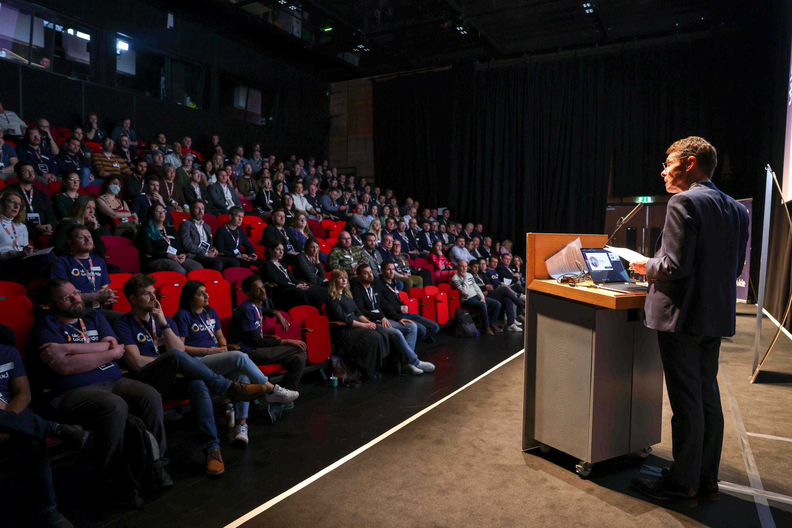 Professional man giving a speech on a stage in front of a crowd at an event