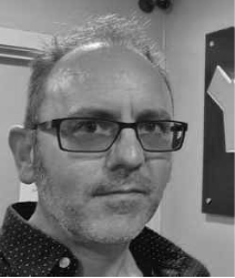 Black and white side profile shot of a man wearing glasses. His name is Simon Byron